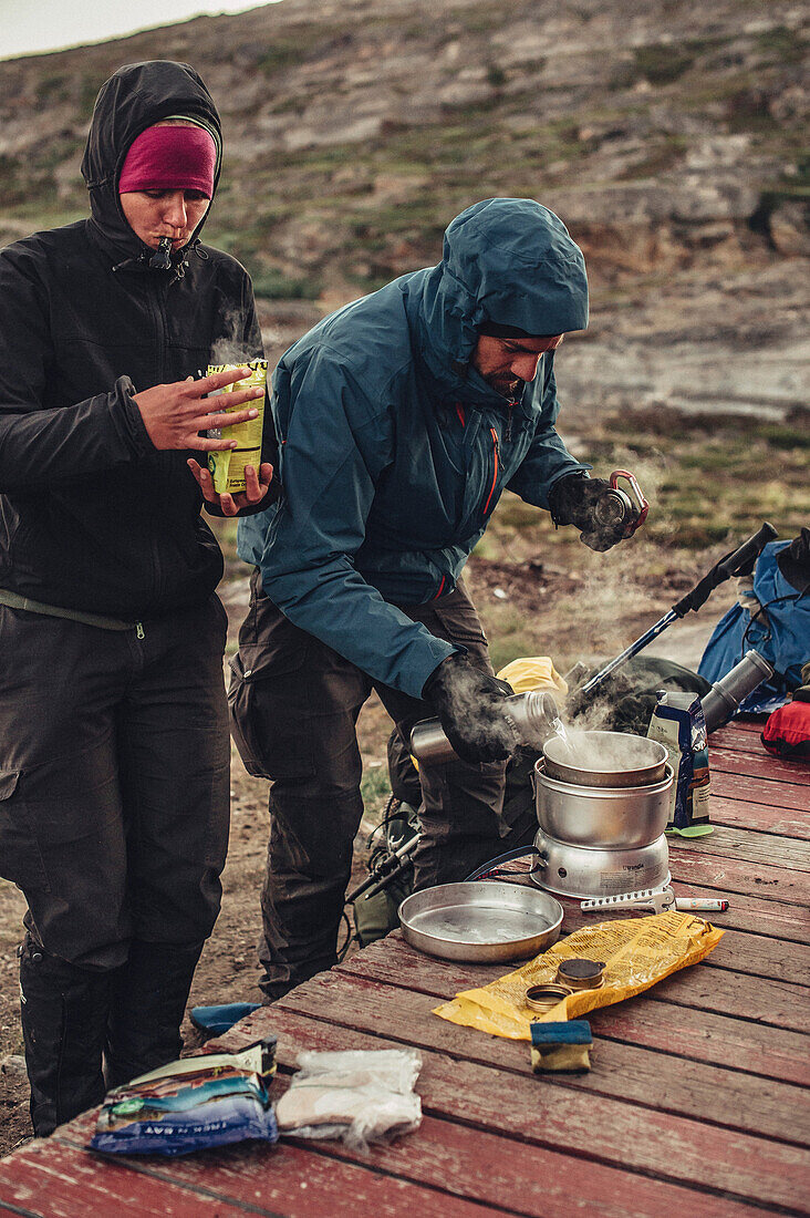 Mann kocht vor einer Hütte, Grönland, Arktis.