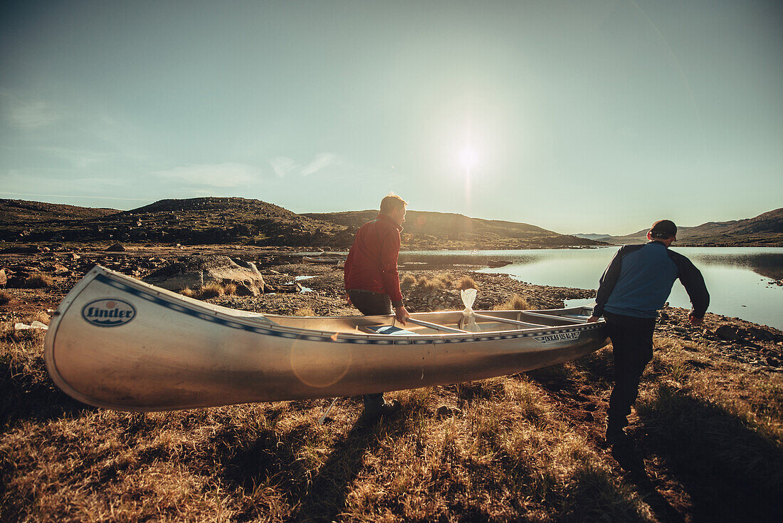Männer tragen ein Ruderboot in Grönland, Grönland, Arktis.