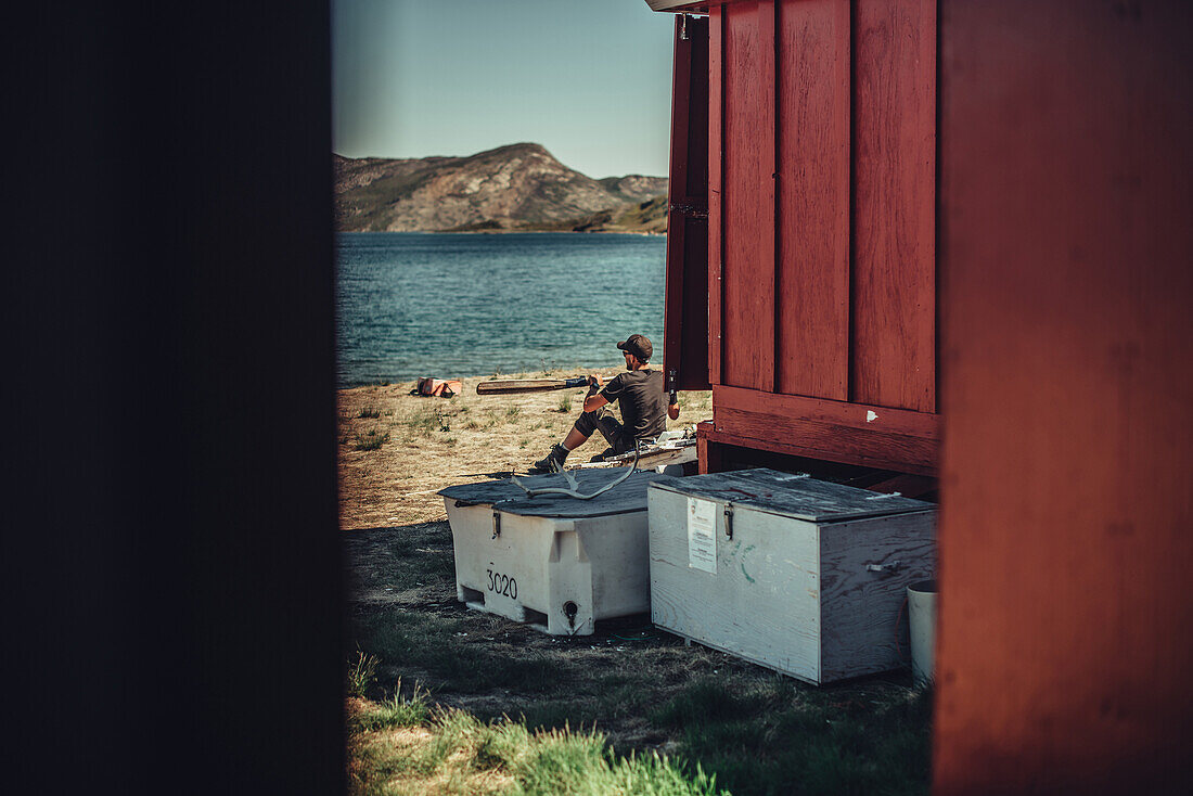 Wanderer vor einer roten Hütte in Grönland, Grönland, Arktis.