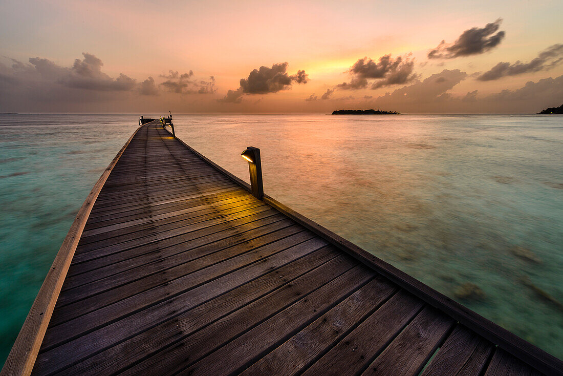 Gebogener Steg bei Sonnenuntergang im Maafushi Atoll, Malediven