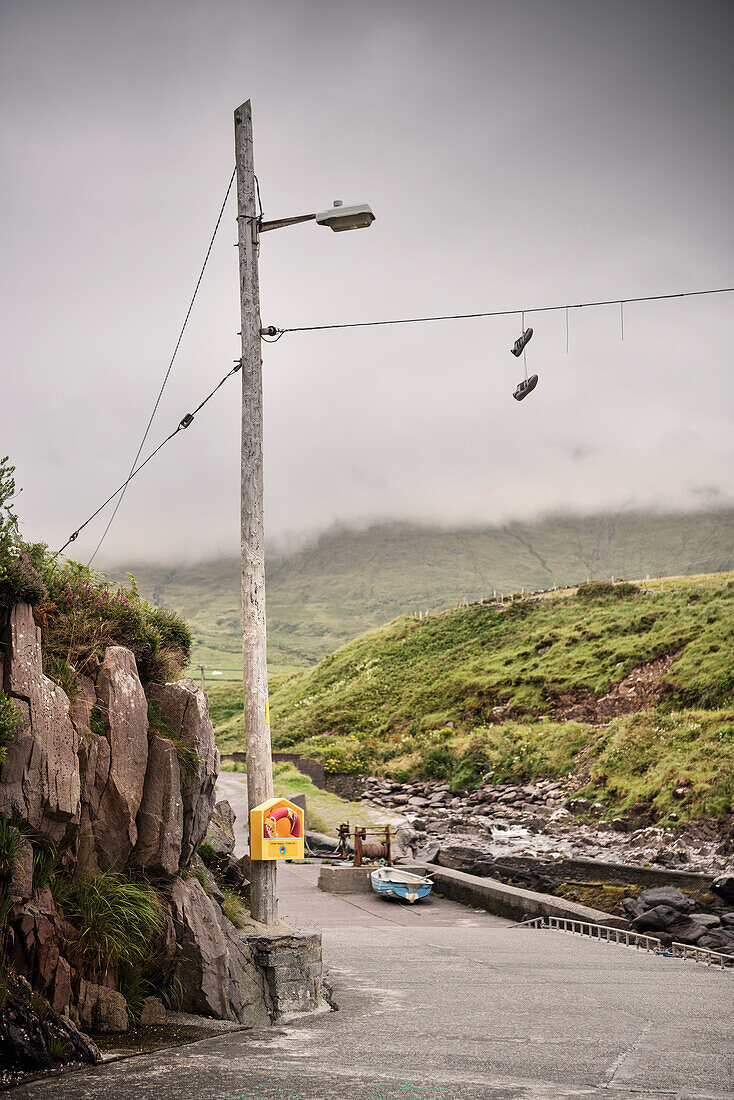 Schuhe hängen an einem Strommast an einem kleinen Hafen, Dingle Halbinsel, Slea Head Drive, Grafschaft Kerry, Irland, Wild Atlantic Way, Europa