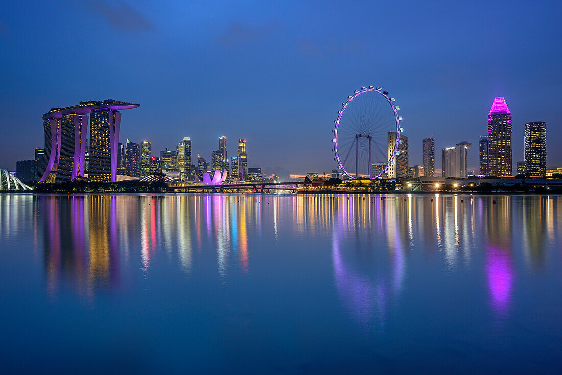 Beleuchtete Skyline von Singapur mit Marina Bay Sands, ArtScience Museum und Singapore Flyer, spiegelt sich in Marina Bay, Singapur