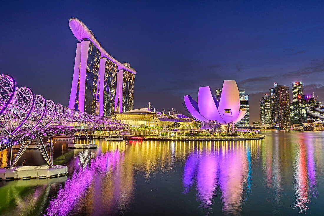 Illuminated skyline of Singapore with Helixbridge, Marina Bay Sands and ArtScience Museum reflecting in Marina Bay, Singapore
