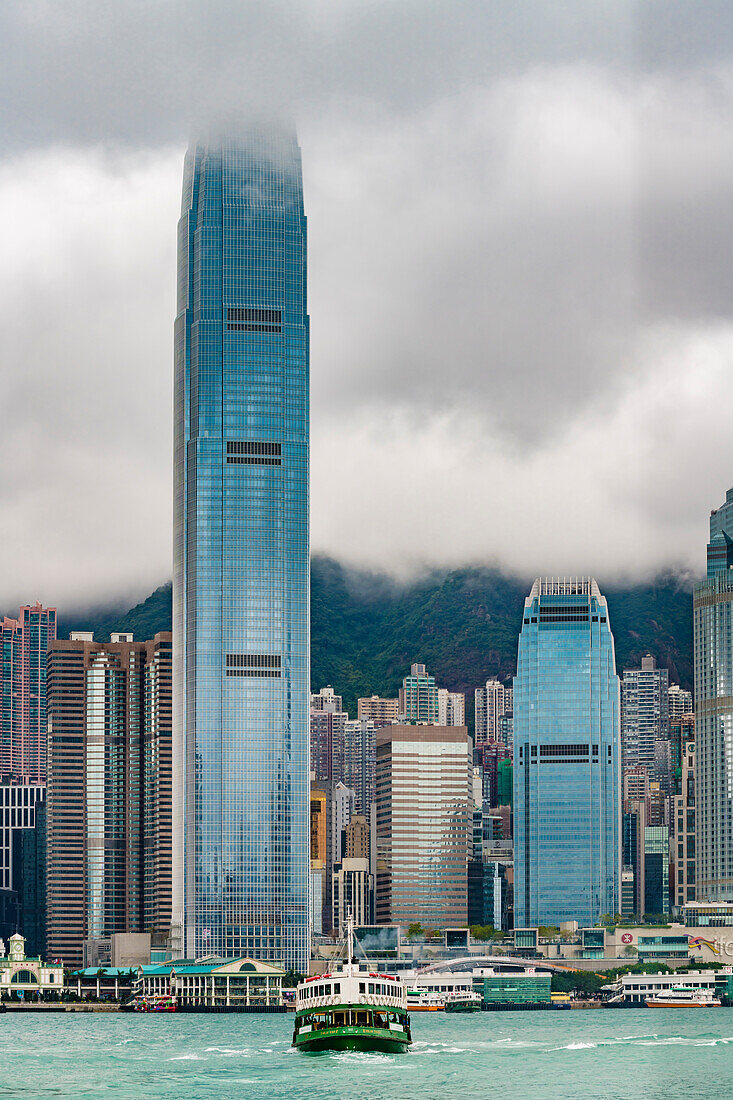 Die Skyline von Hongkong Island mit dem Stadtberg The Peak im Dunst und einer Star Ferry im Viktoria Harbour, Hongkong, China, Asien