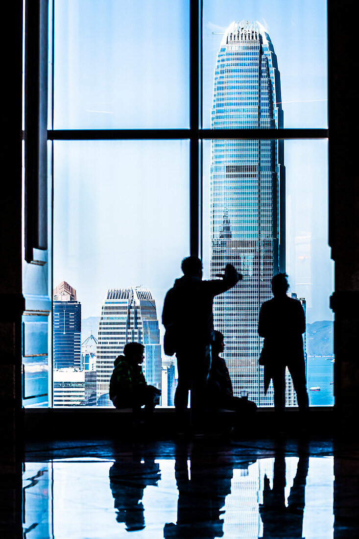 A group of visitors in the Central Plaza high-rise building overlooks the Two International Finance Centre skyscraper on Hong Kong Island, Hong Kong, China, Asia