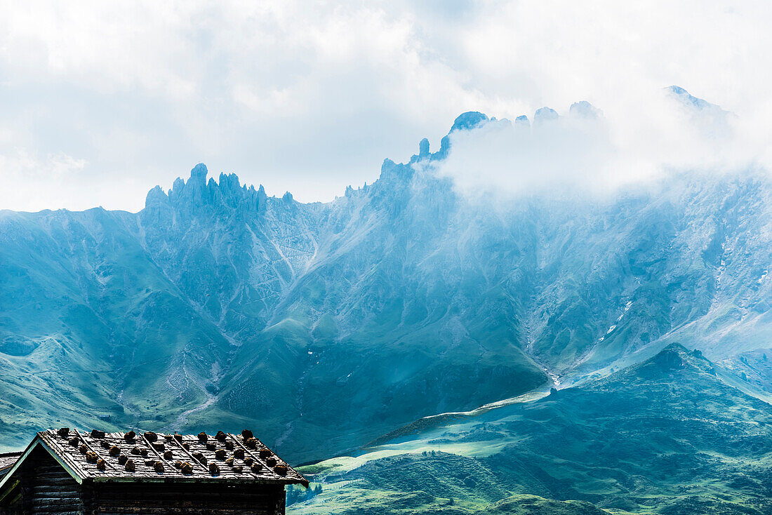Typical wooden hut on the Alpe di Siusi with a view of the mountain range Schlern and Rosszahnscharte, Compatsch, South Tyrol, Alto Adige, Italy