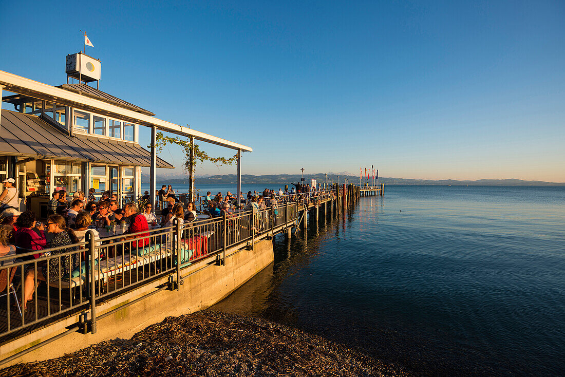 Menschen auf Steg bei Sonnenuntergang, Schiffsanlegestelle Kressbronn, Bodensee, Baden-Württemberg, Deutschland