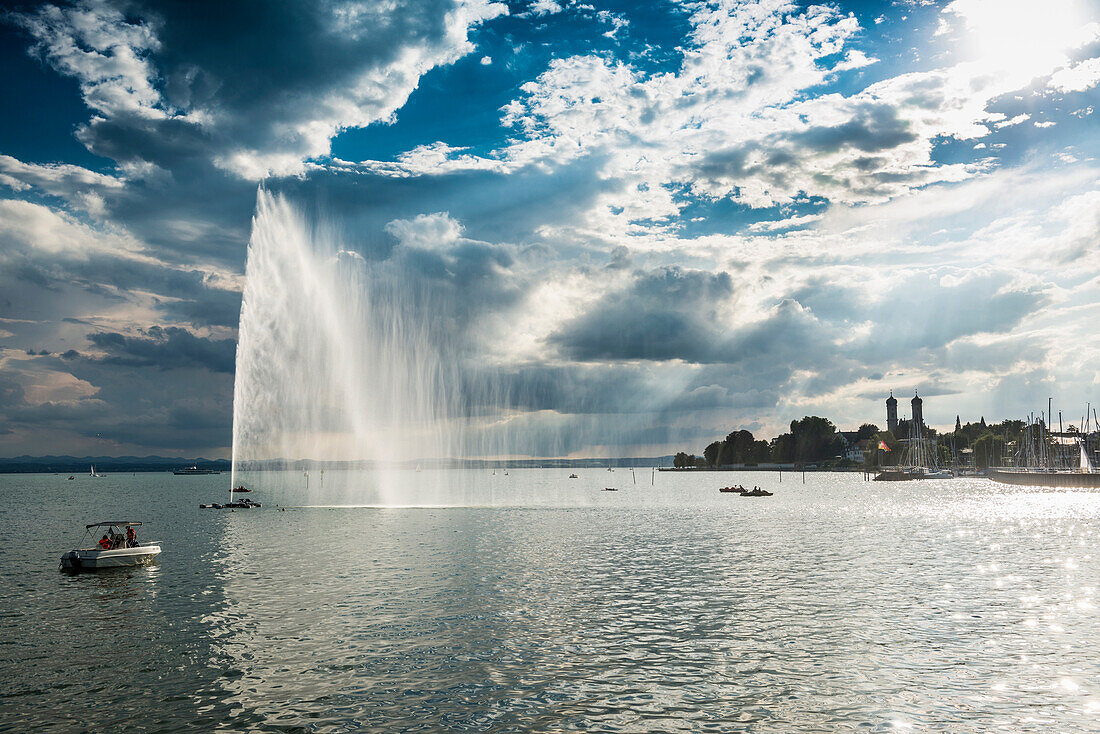 Fontäne und Gewitterwolken bei Sonnenuntergang, hinten die Schlosskirche, Friedrichshafen, Bodensee, Baden-Württemberg, Deutschland