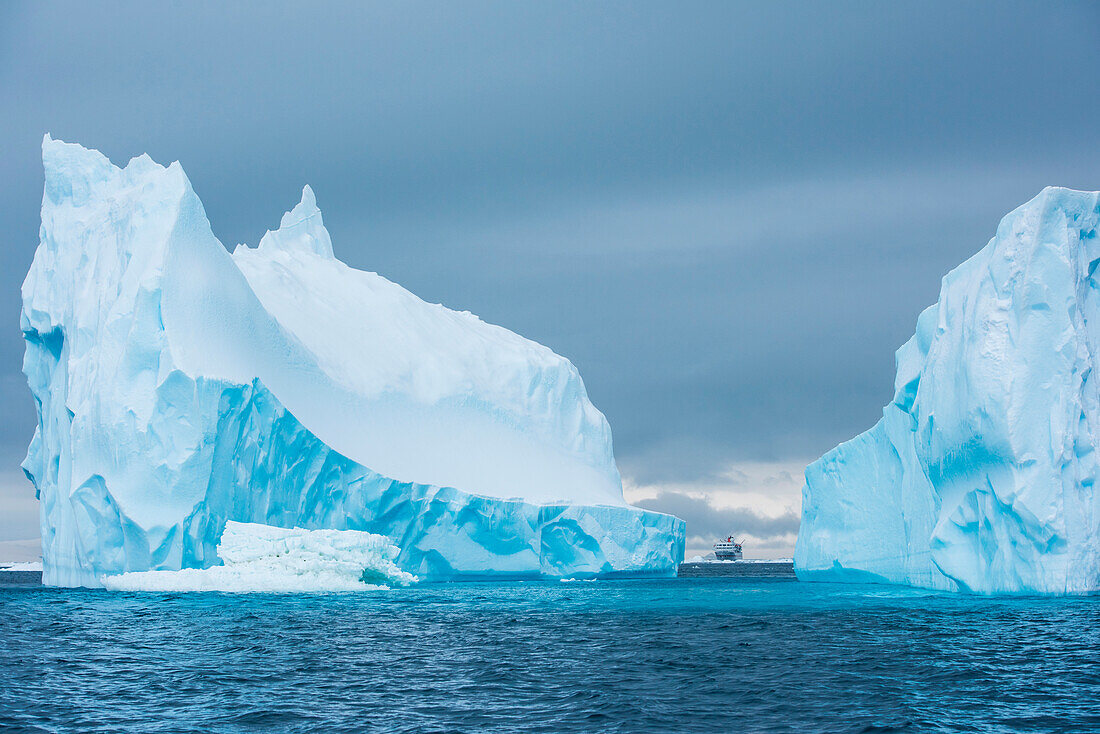The expedition cruise-ship MS Bremen (Hapag Lloyd) is dwarfed by a towering iceberg, Active Sound, Antarctica