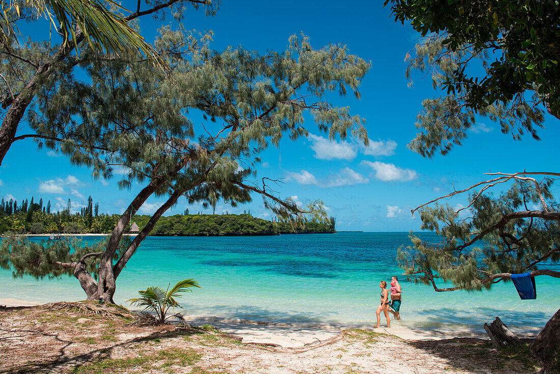 Eine Frau und ein Mann der ein Baby trägt spazieren entlang einen idyllischen Strand, Ile des Pins, Neukaledonien, Südpazifik