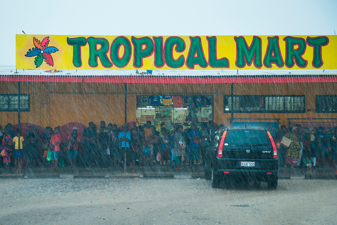 Viele Menschen stehen unter einem Vorzelt für den Tropical Mart um starken Regen zu vermeiden, Rabaul, East New Britain, Papua-Neuguinea, Südpazifik