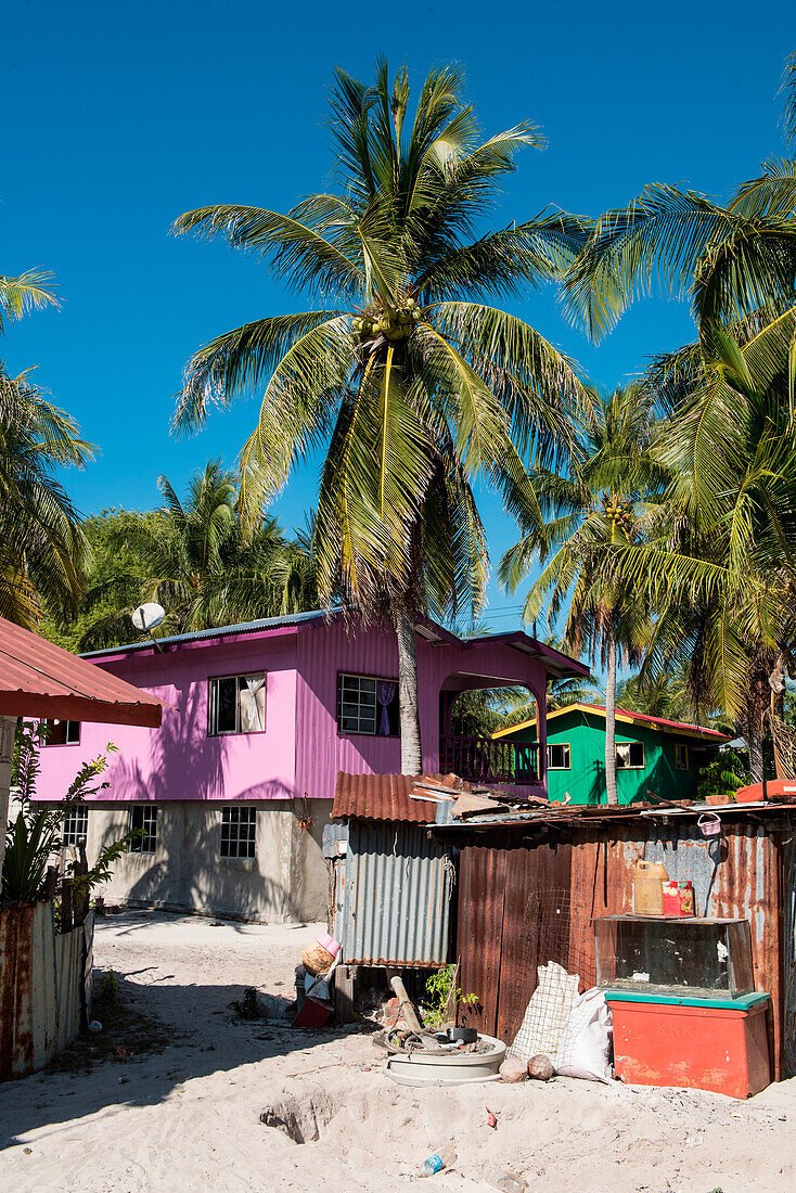 Ein bunt bemaltes zweistöckiges Holzhaus steht in Kontrast zu einer Wellblechhütte in einem Fischerdorf auf Pulau Mantanani, Mantanani-Inseln, nahe Sabah, Malaysia, Asien