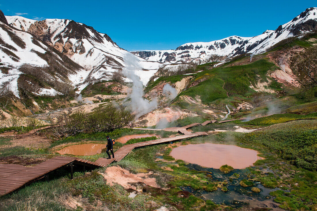 A German tourist walks on a boardwalk amidst steaming pools of water in the Valley of Geysers (UNESCO World Heritage Site), near Petropavlovsk-Kamchatsky, Kamchatka, Russia, Asia