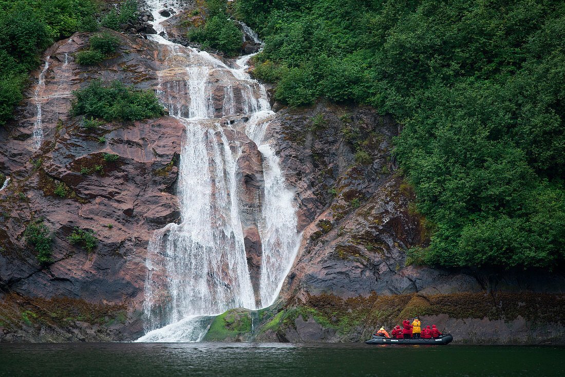 Passengers in a Zodiac raft of expedition cruise ship MS Bremen (Hapag-Lloyd Cruises) photograph a waterfall running across a sheet of rock, Misty Fjords National Monument, Tongass National Forest, Alaska, USA, North America
