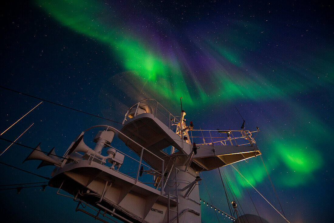 Die Nordlichter (auch Polarlichter oder Aurora Borealis) erhellen den Himmel kurz nach Sonnenuntergang, gesehen von an Bord Expeditions-Kreuzfahrtschiff MS Bremen (Hapag-Lloyd Cruises), zwischen Nordostkap und Kap Ossory, Nunavut, Nordkanada, Nordamerika