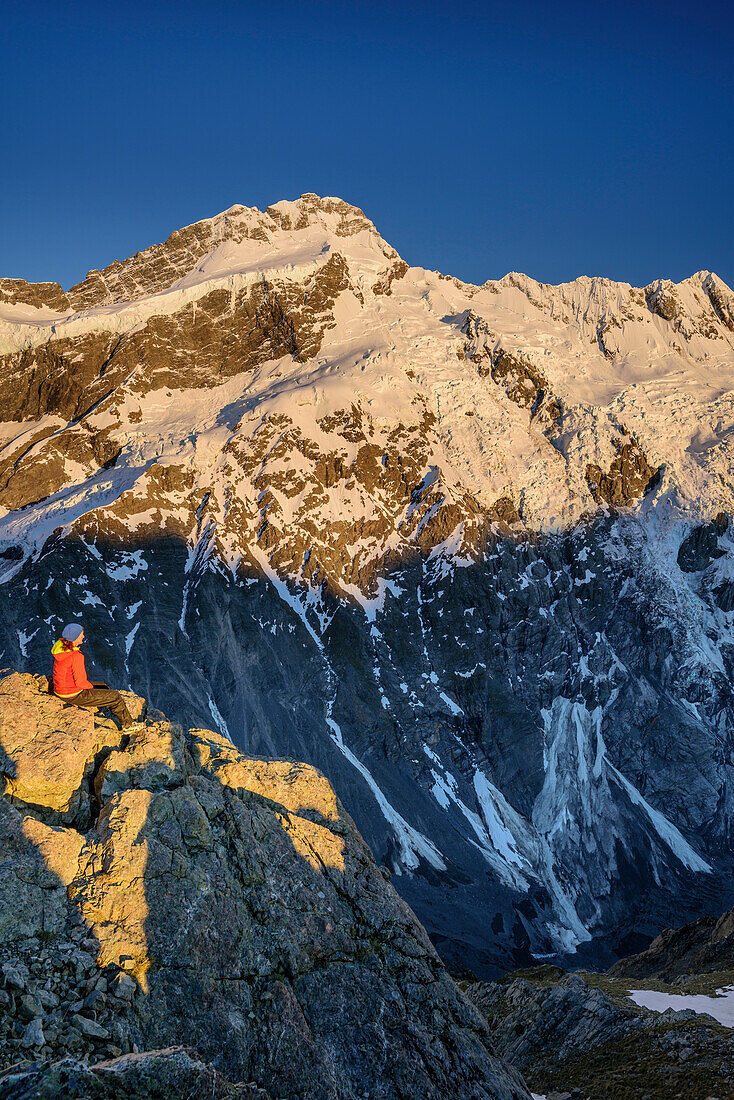 Woman sitting on rock and looking towards Mount Sefton and Footstool, from Mueller Hut, Hooker Valley, Mount Cook National Park, UNESCO Welterbe Te Wahipounamu, Lake Pukaki, Canterbury, South island, New Zealand