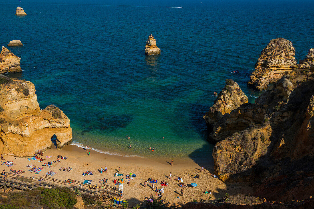 Badegäste am Strand zwischen steilen Felsen, Praia do Camilo, Lagos, Algarve, Portugal