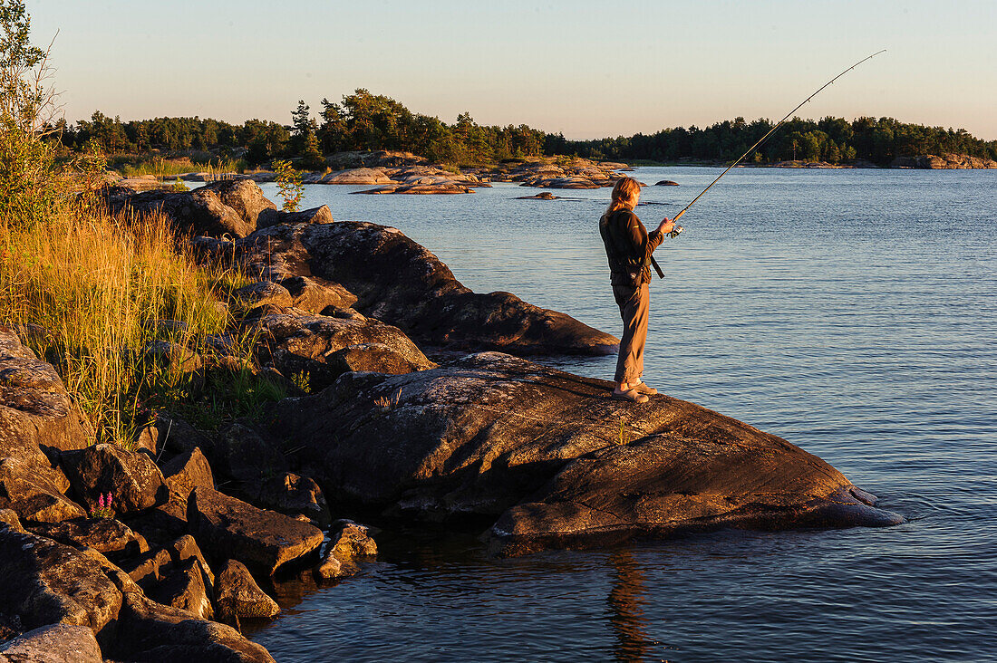 Woman fishing, Kaellandsoe on Lake Vänern, Sweden