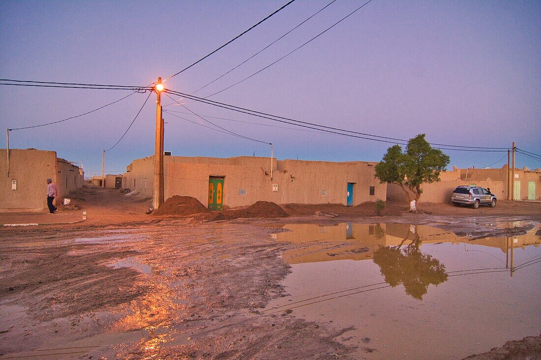 Mud-walled houses and wet muddy road after a very rare rain after sunset at Merzouga near Rissani in the Ziz Valley, Morocco