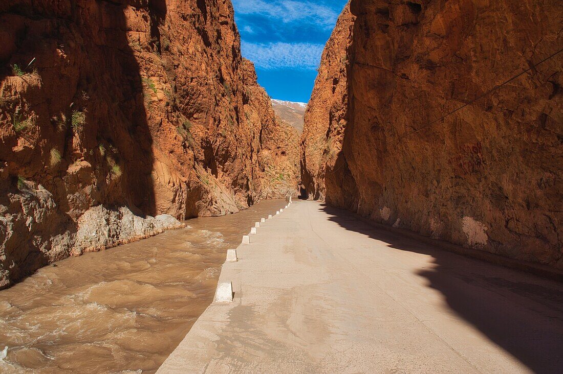 Cliffs of the Dadés gorge with orange rocks,  small road beside a river passing the gorge, High Atlas, Morocco