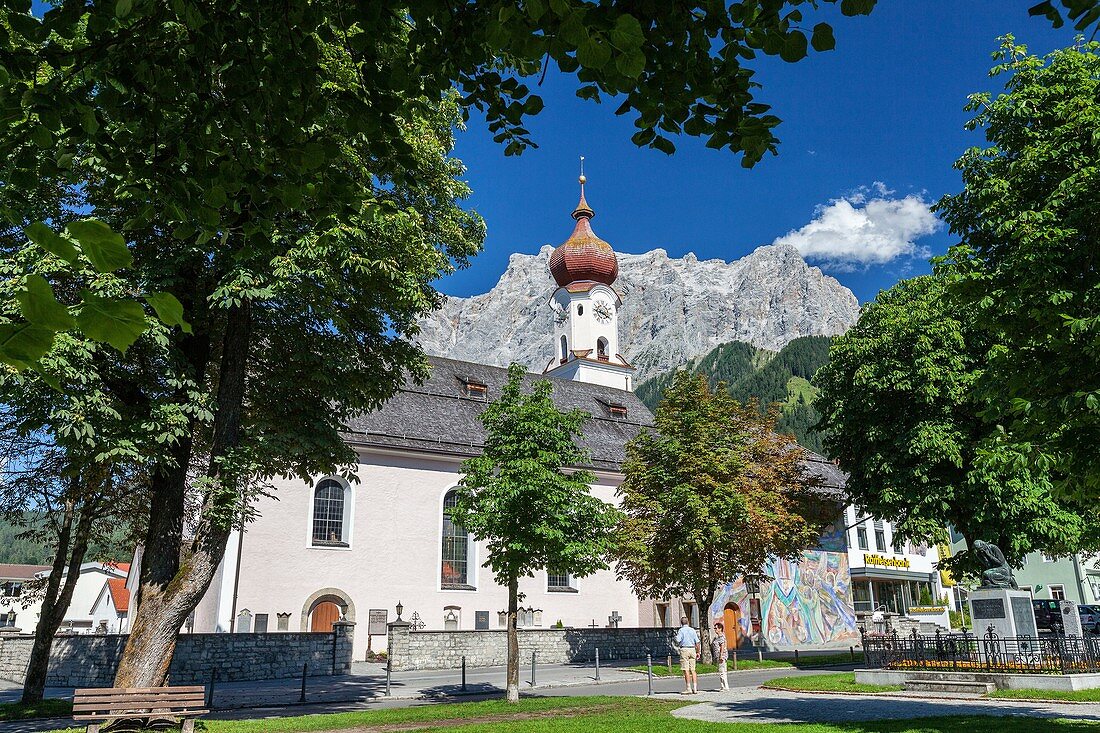 Typical church of alpine village surrounded by peaks and woods Garmisch Partenkirchen Oberbayern region Bavaria Germany Europe.