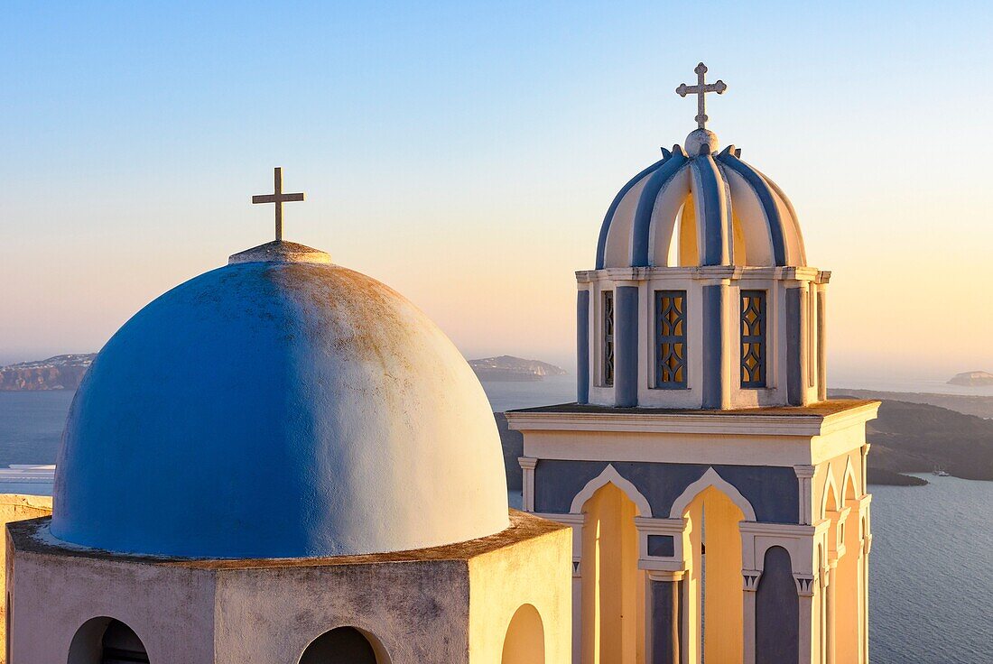 Sunset over a blue domed church on Santorini Island, Cyclades, Greece.