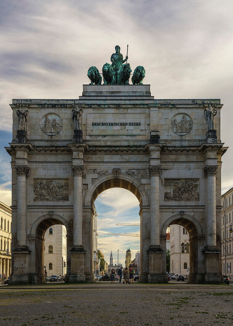 Blick auf das Siegestor mit Quadriga, durch das Tor blickt man die Ludwigstrasse entlang auf den Odeonsplatz und sieht den Rathausturm, die Theatinerkirche und die Feldherrnhalle, München, Oberbayern, Deutschland