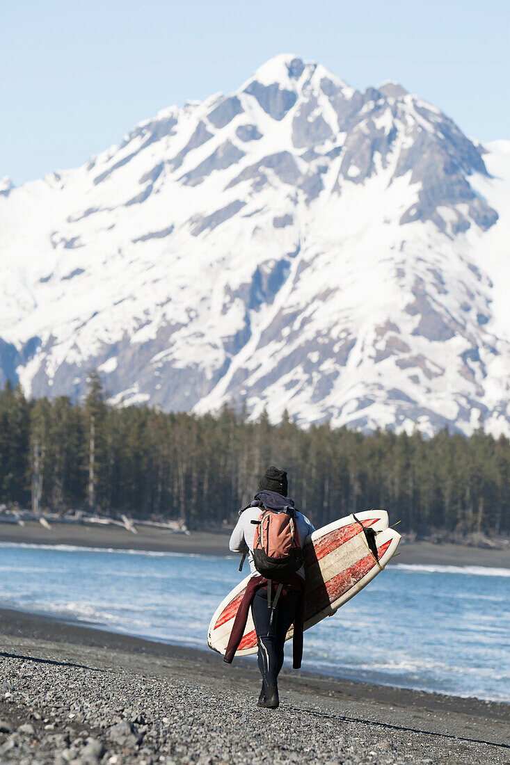 Surfer Walking With Surfboard Along The Kenai Peninsula Outer Coast, Southcentral Alaska, USA