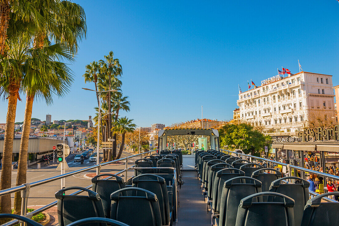 Seats In A Tour Bus With A View Of The Pedestrians, Palm Trees And Buildings In The French Riviera; Cannes, Cote D'azur, France