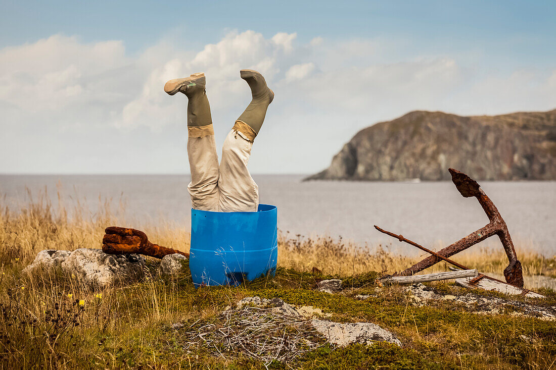Sculpture of man's legs wearing rubber boots upside down in a barrel along the Atlantic coast; Newfoundland, Canada