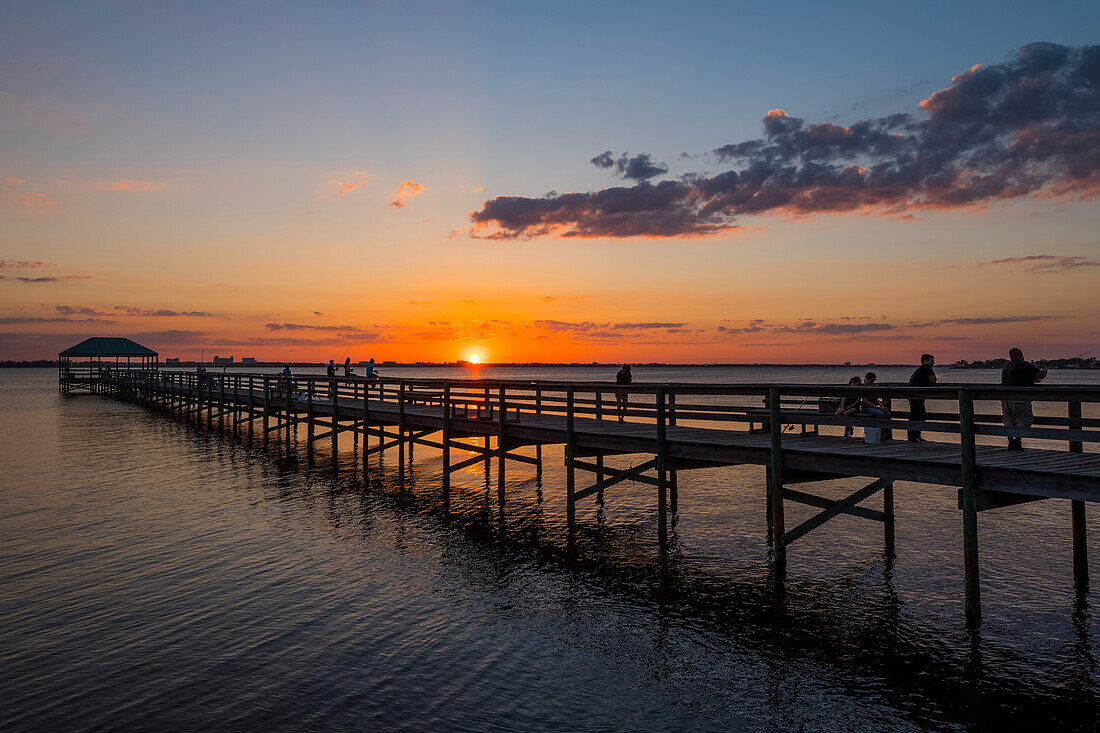 People standing on a pier as the sun sets over the Indian River; Indialantic, Florida, United States of America