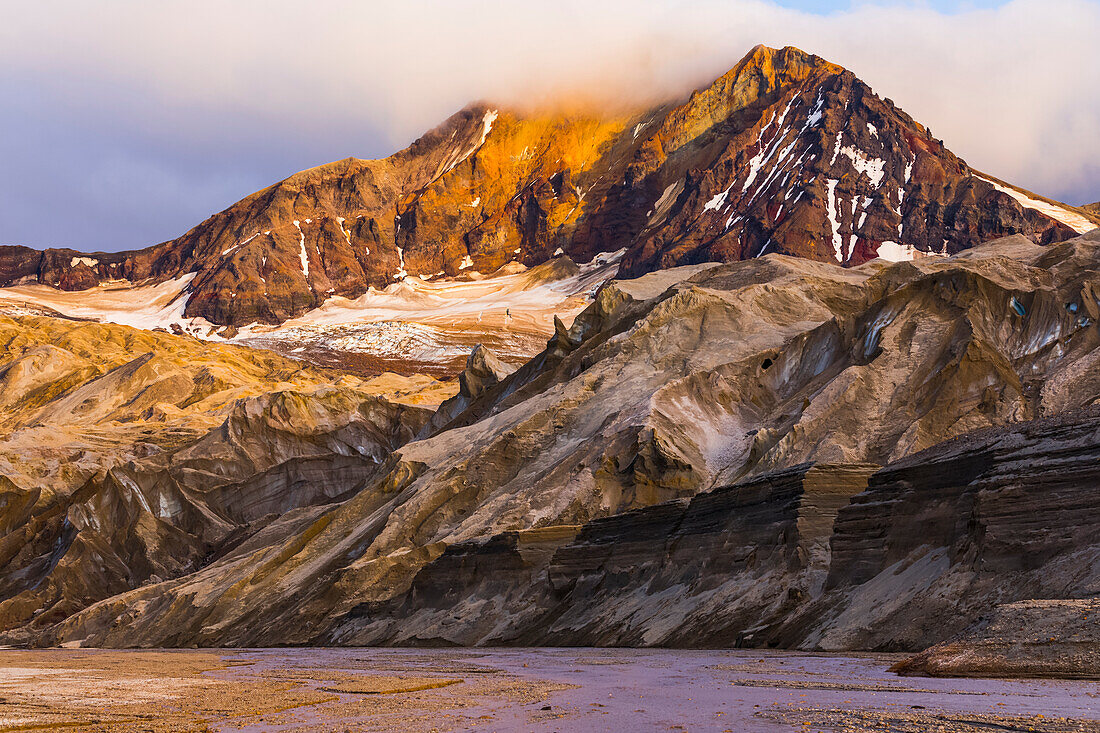 The eastern peak of Trident Volcano rises above the ash-covered Knife Creek Glaciers at sunset in Katmai National Park; Alaska, United States of America