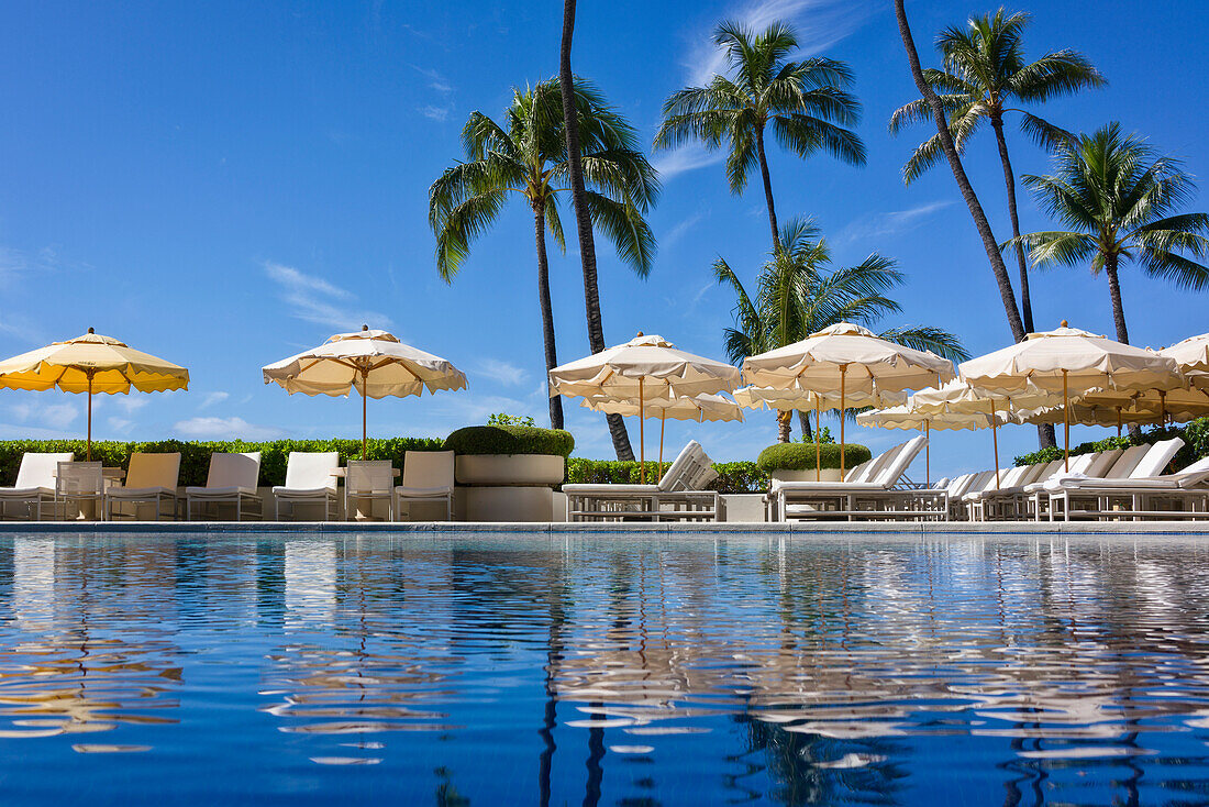 Halekalani Pool at Waikiki with palm trees and umbrellas reflected in the water; Waikiki, Oahu, Hawaii, United States of America