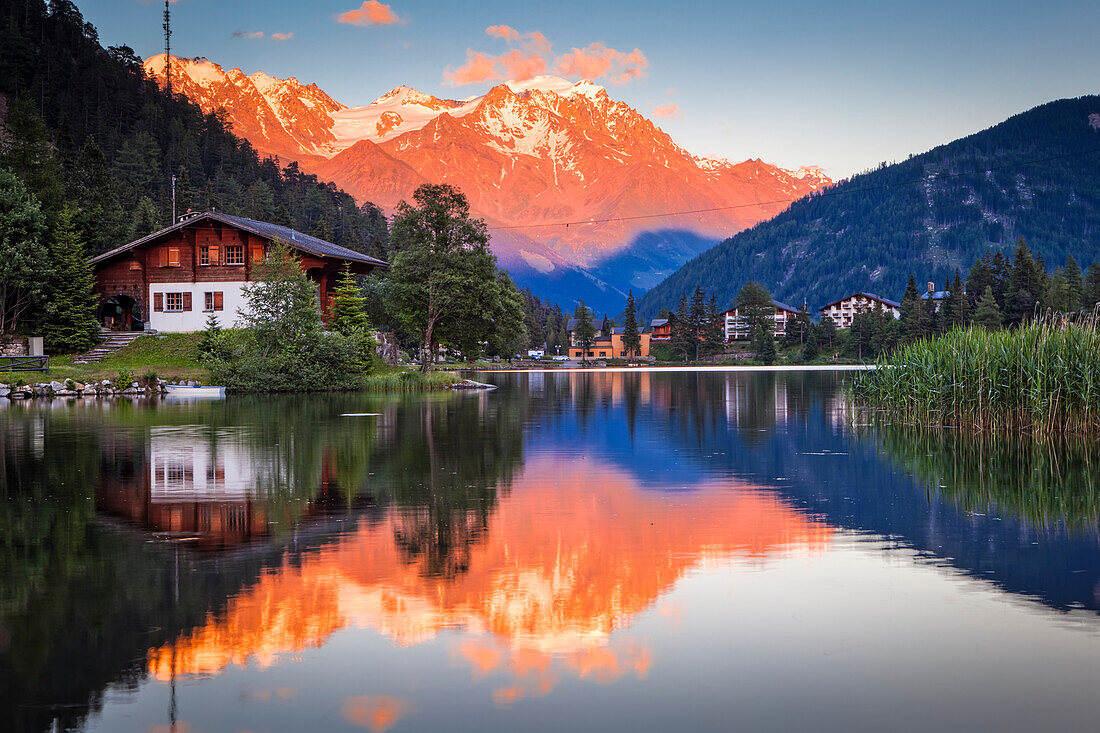 Pastel-coloured sunset glow on the mountains reflecting on Champex Lake; Champex, Valais, Switzerland