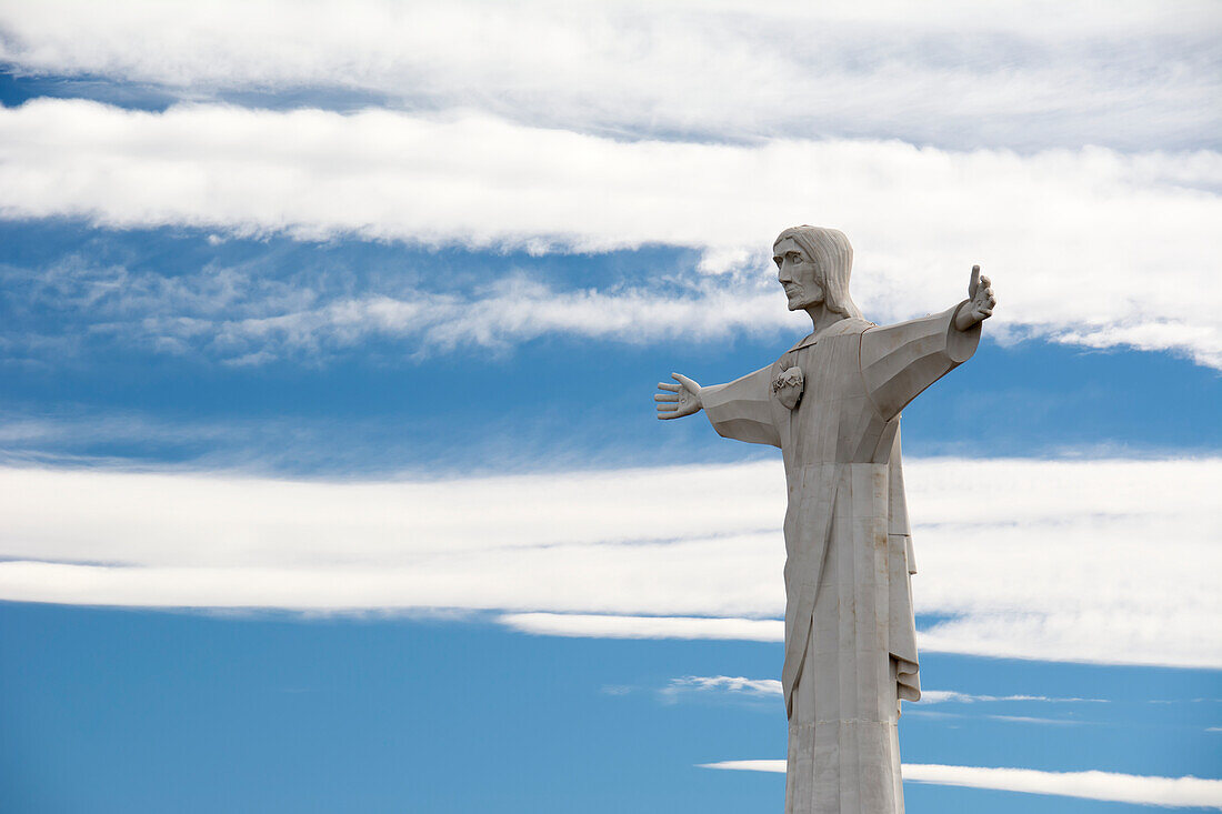 Statue Of Christ Against Blue Sky With Stripes Of White Clouds; Tupungato, Mendoza, Argentina