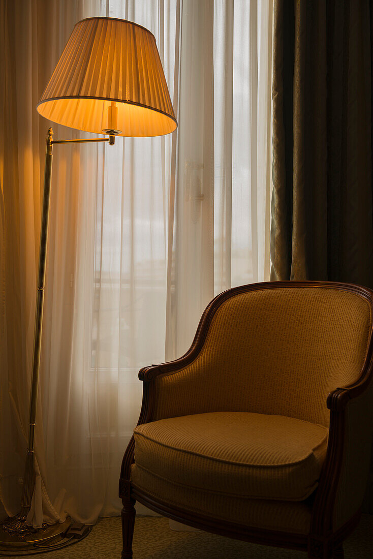 A Floor Lamp Illuminated Beside A Chair And Window; Cannes, Cote D'azur, France