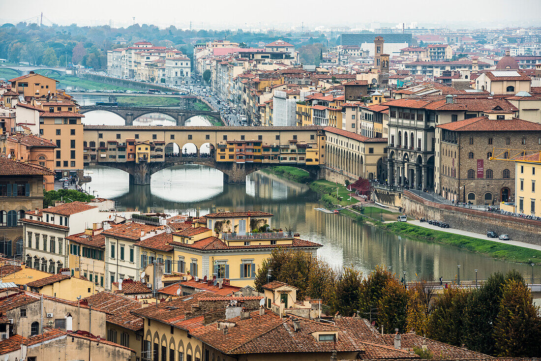 View Of Buildings, Colourful Roofs, Ancient Bridges (Ponte Vecchio) And Bending Arno River; Florence, Tuscany, Italy