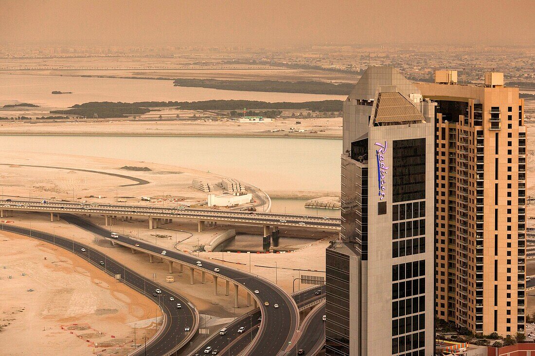 UAE, Dubai, Downtown Dubai, elevated desert and highway view towards Ras Al Khor with Radisson Hotel, dusk.