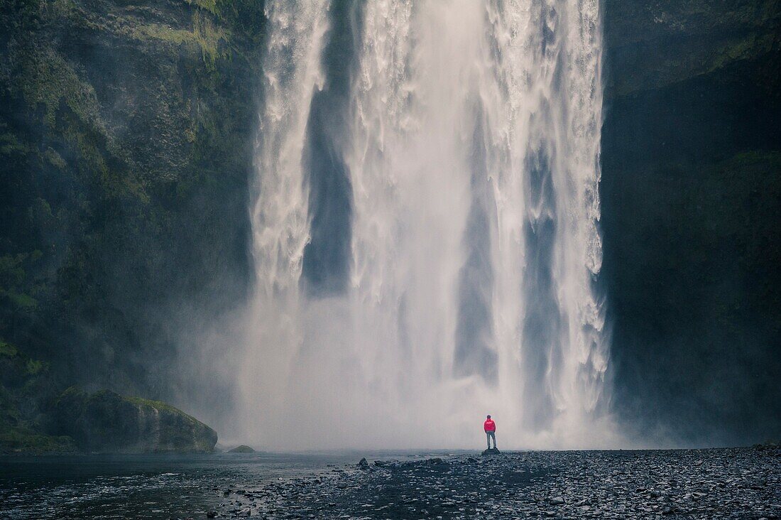 Southern Iceland. Man stands below the Skogafoss waterfall.