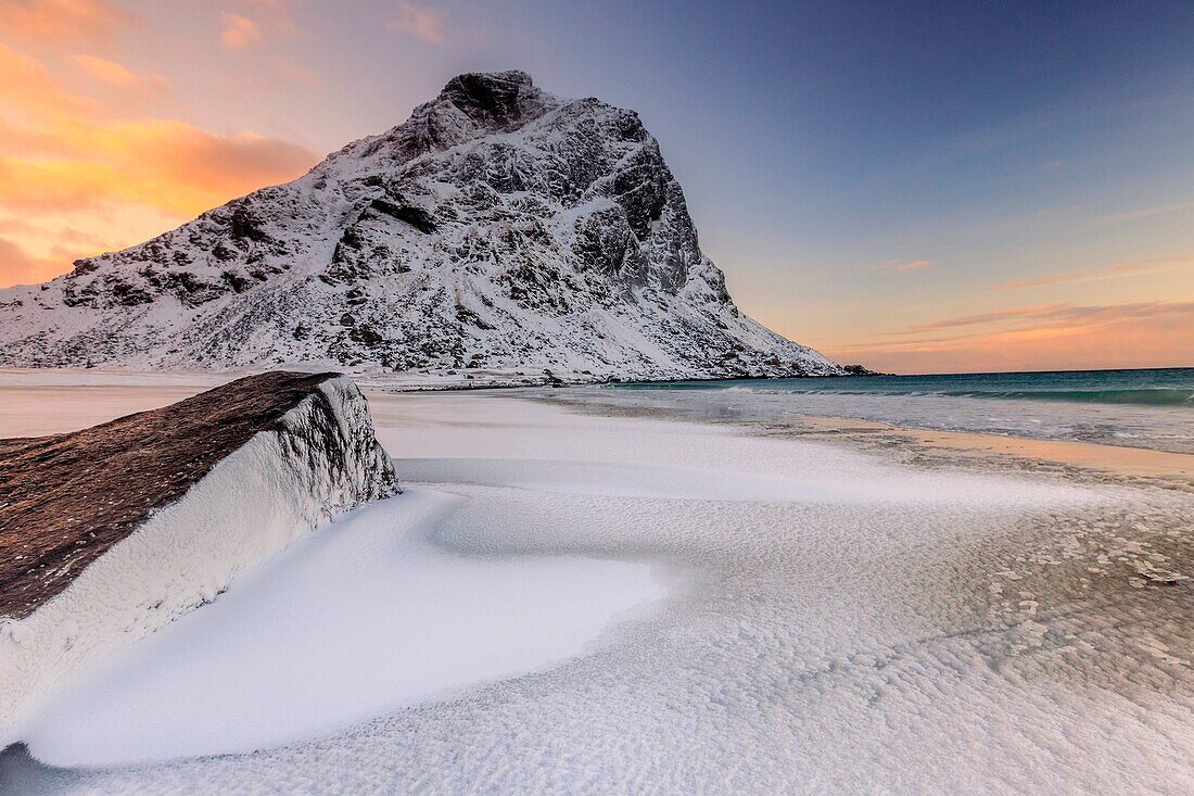 Dawn illuminates the rocks shaped by wind surrounded by fresh snow. Uttakleiv Lofoten Islands Norway Europe.