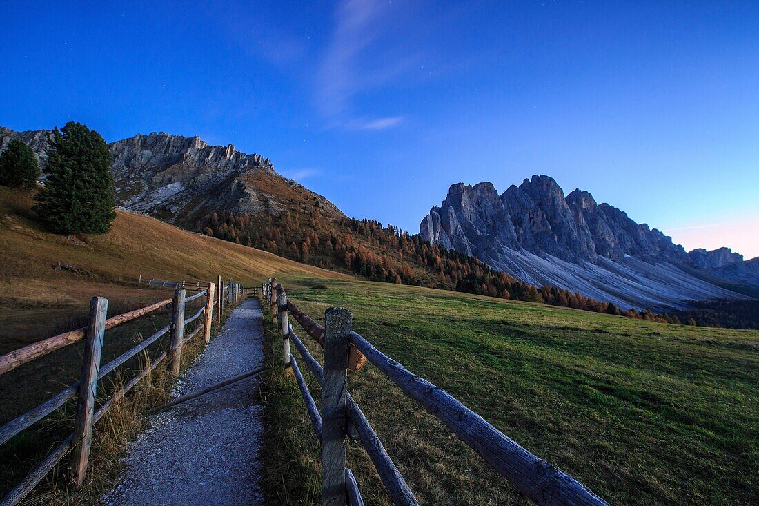 Green meadows and colorful woods in autumn frame the Odle. Funes Valley South Tyrol Dolomites Italy Europe.