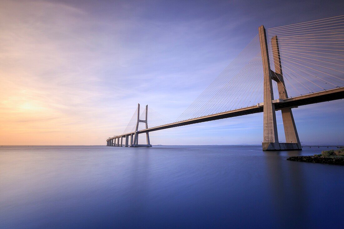 The colors of dawn on Vasco da Gama Bridge that spans the Tagus River in Parque das Nações Lisbon Portugal Europe.