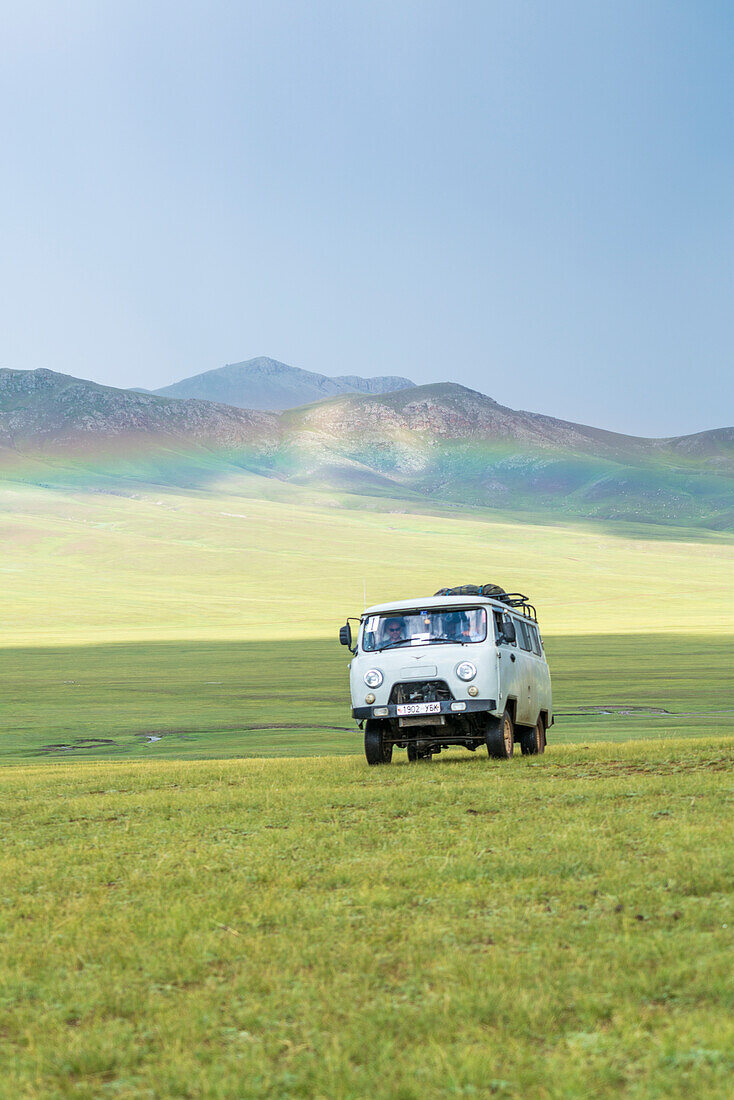 Rainbow and Soviet vehicle driving in the Mongolian steppe. Ovorkhangai province, Mongolia.