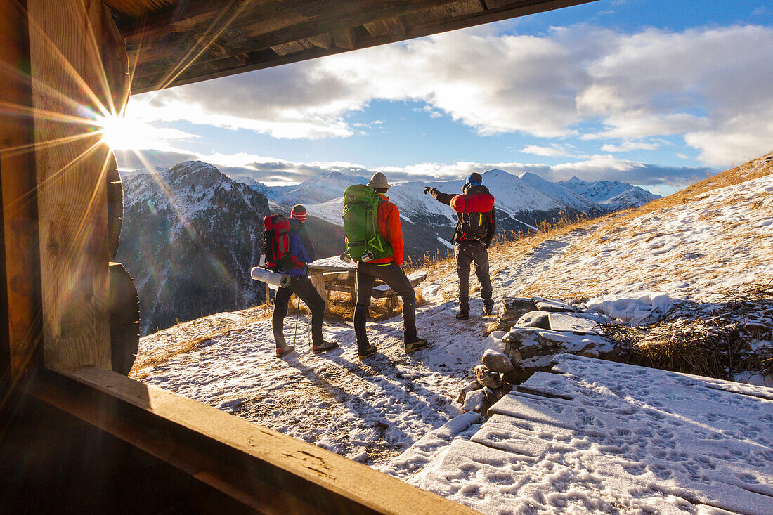 Hikers admiring sunrise from an alpine hut, Livigno, Valtellina, Italy