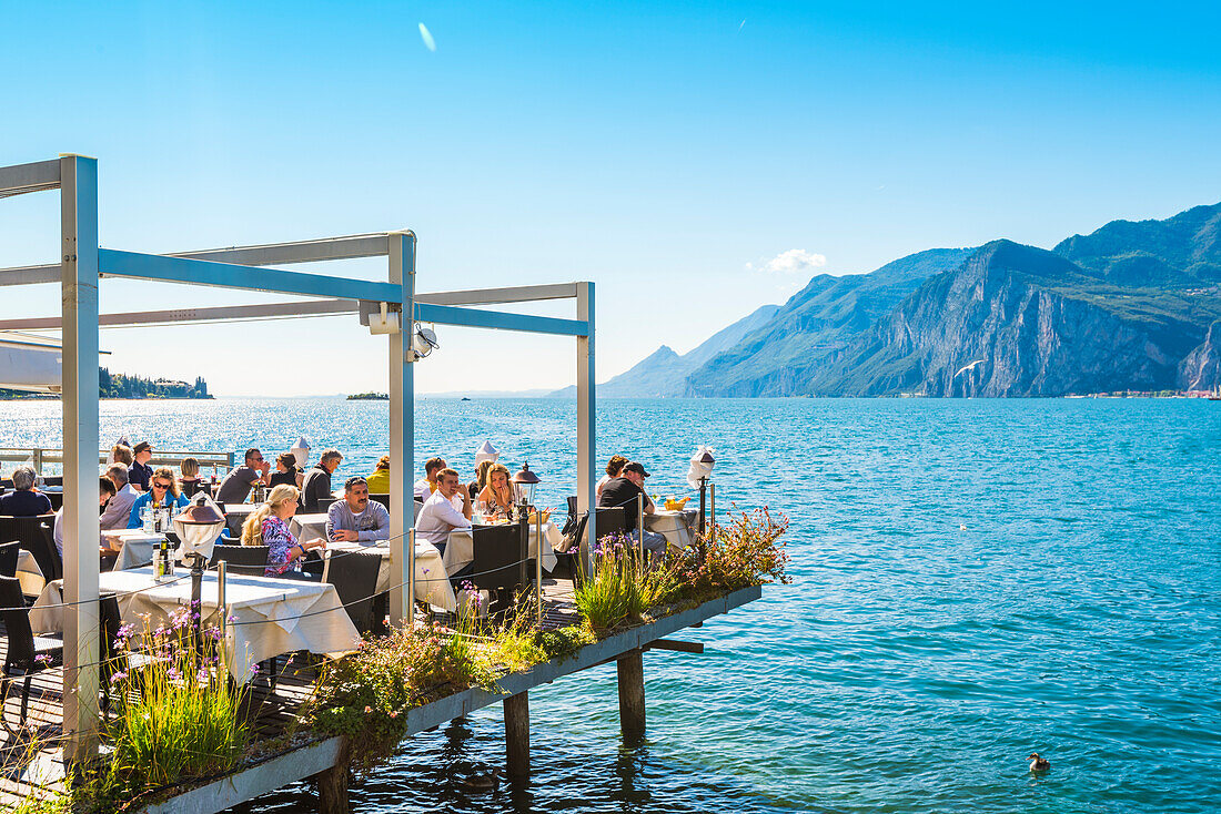 Malcesine, lake Garda, Verona province, Veneto, Italy. Tourists eating out in a restaurant on water.