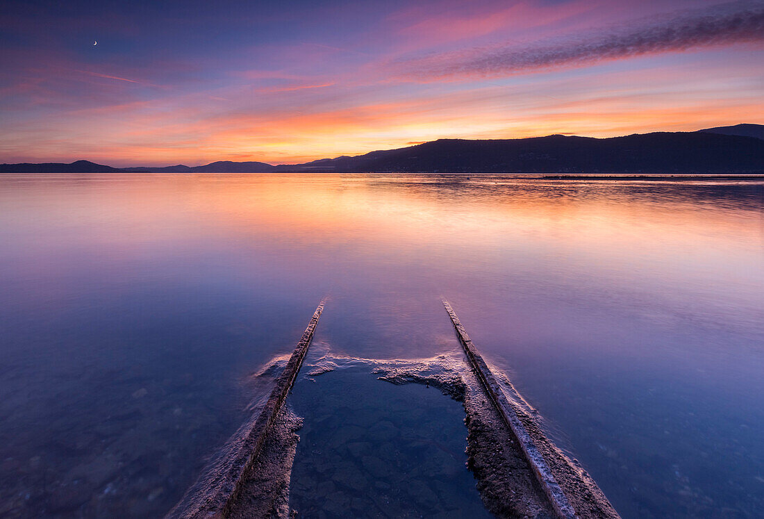 Emerged boat rails at Sasso Moro dock during an autumnal sunset, Sasso Moro, Leggiuno, Lake Maggiore, Varese Province, Lombardy, Italy.