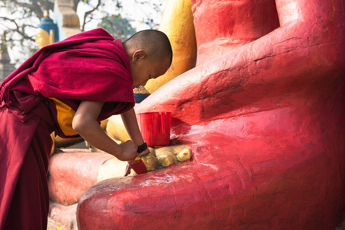 Swayambhunath,Katmandu,Nepal Young monk painting the statue at Swayambhunath temple