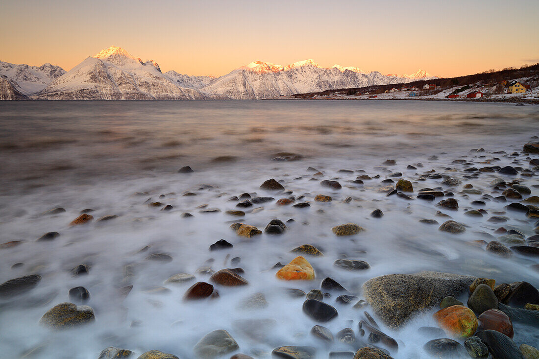 Cloudless sunrise with ice covering the stones on the shore of Balsfjorden, Markenes, Balsfjorden, Lyngen Alps, Troms, Norway, Lapland, Europe