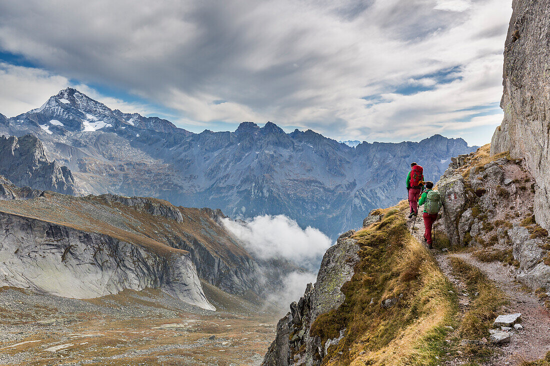 Lombardy, Italy, Trekkers at Qualido pass, in the background Disgrazia peak, Masino valley