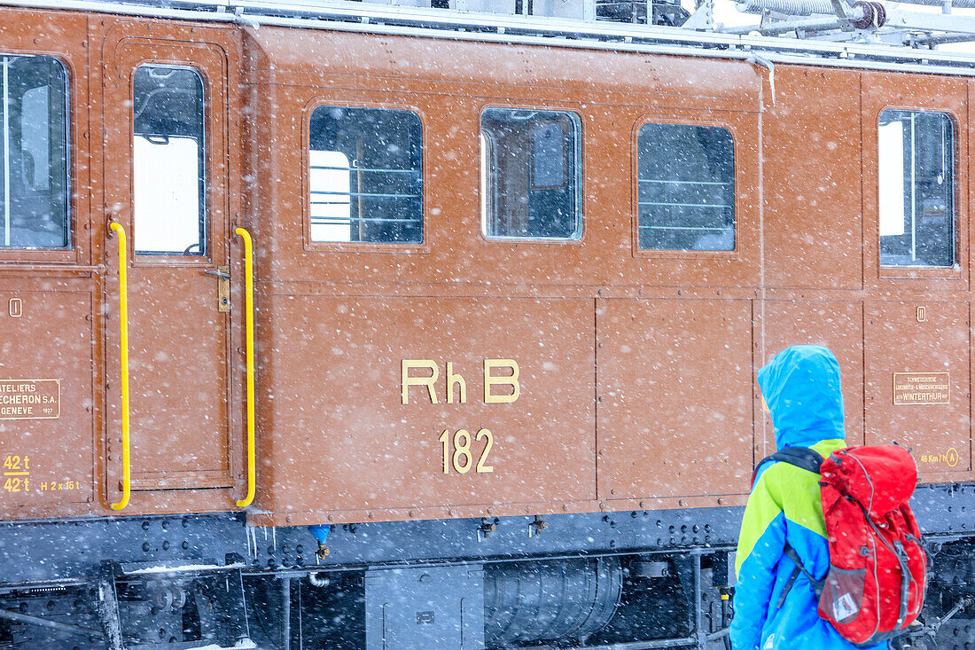 Man looks the snowplow of Bernina Express train, Ospizio Bernina, Poschiavo, canton of Graubünden, Engadin Valley, Switzerland